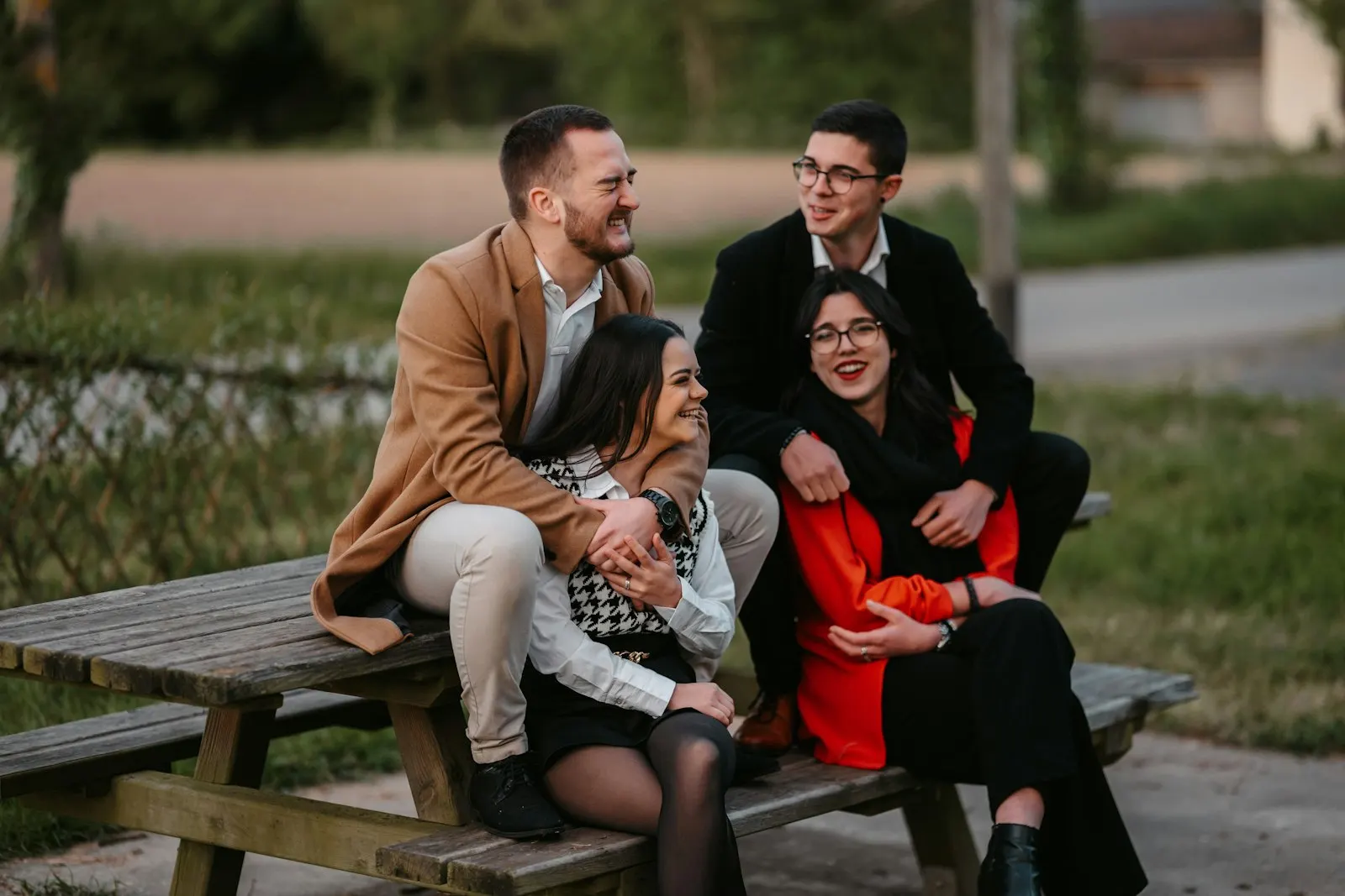 Two young couples laughing together on a park bench