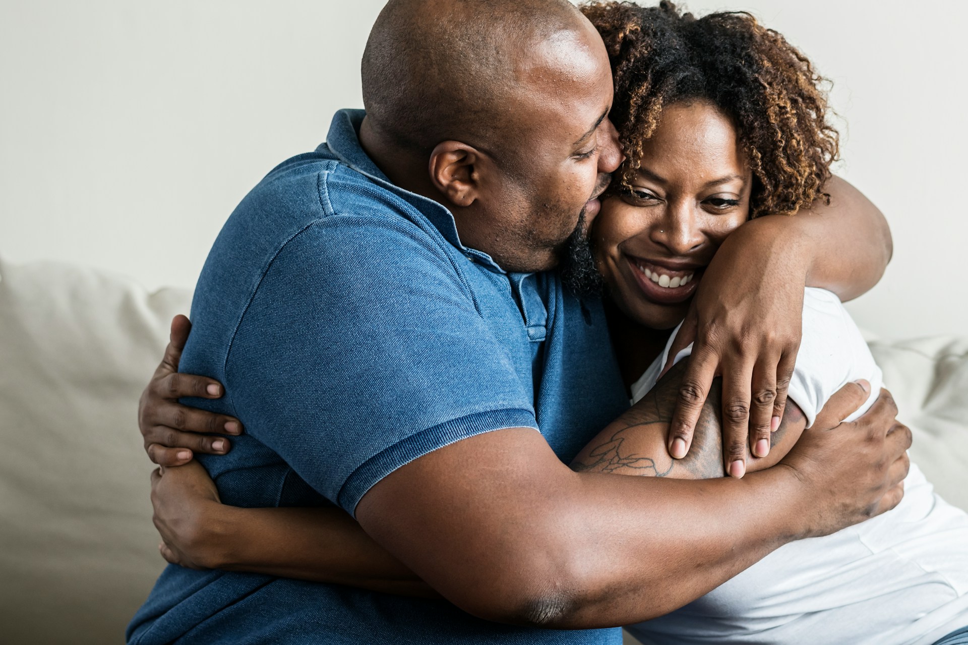 Couple embracing on a sofa, with the husband kissing his wife's forehead
