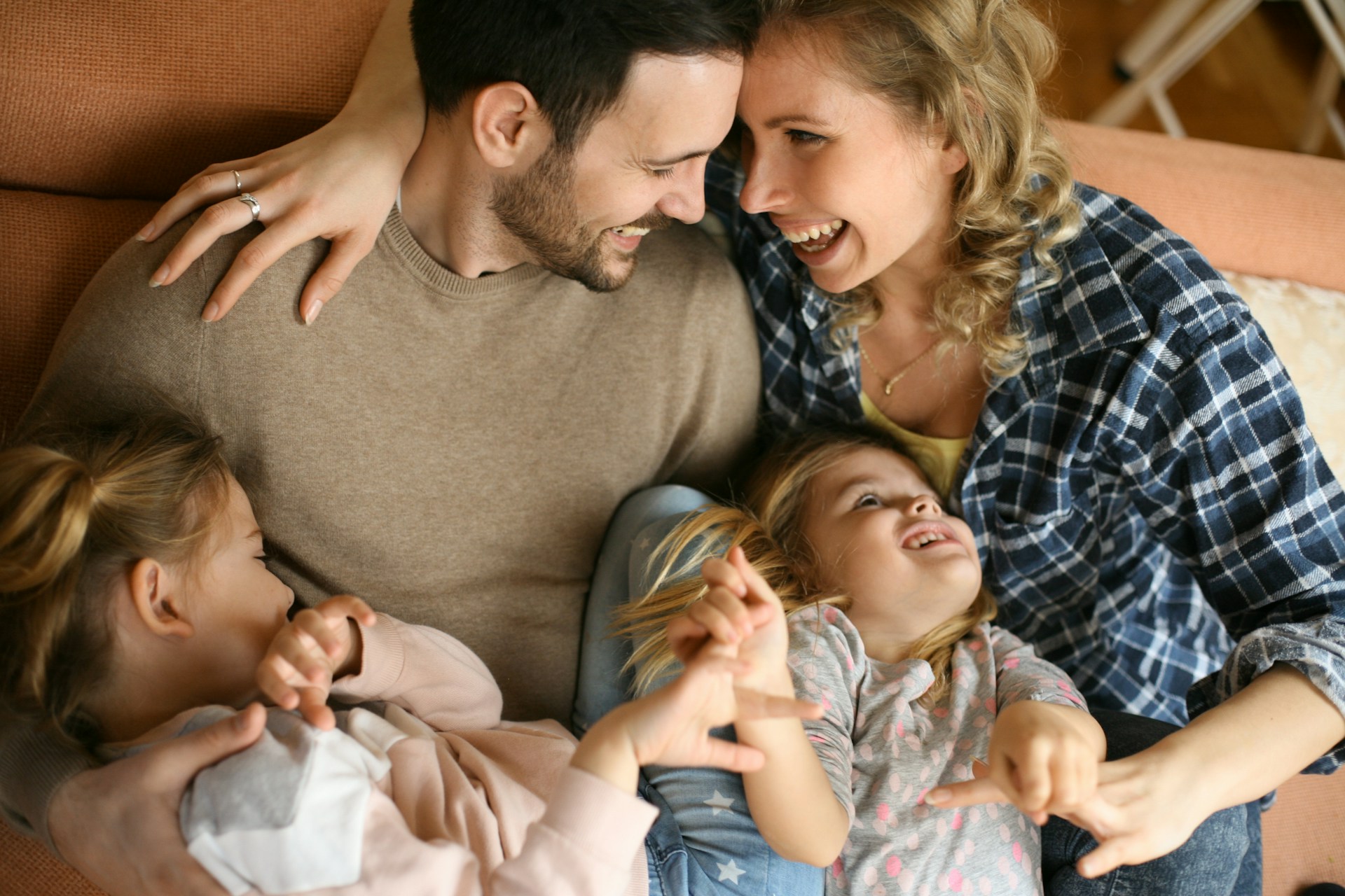 Parents laughing together with their two children on a sofa