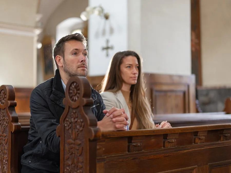 A married couple sitting close together in a church pew