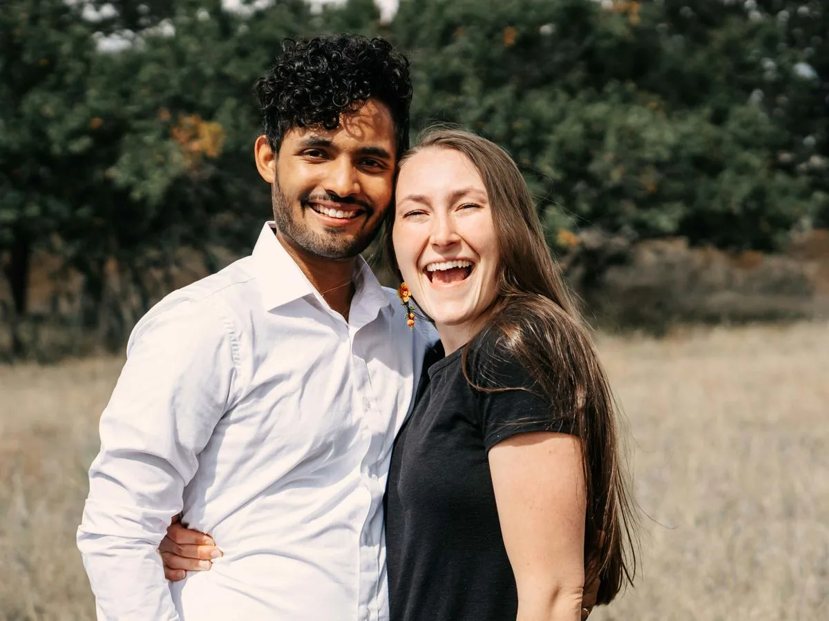 A smiling married couple embracing in a grassy field