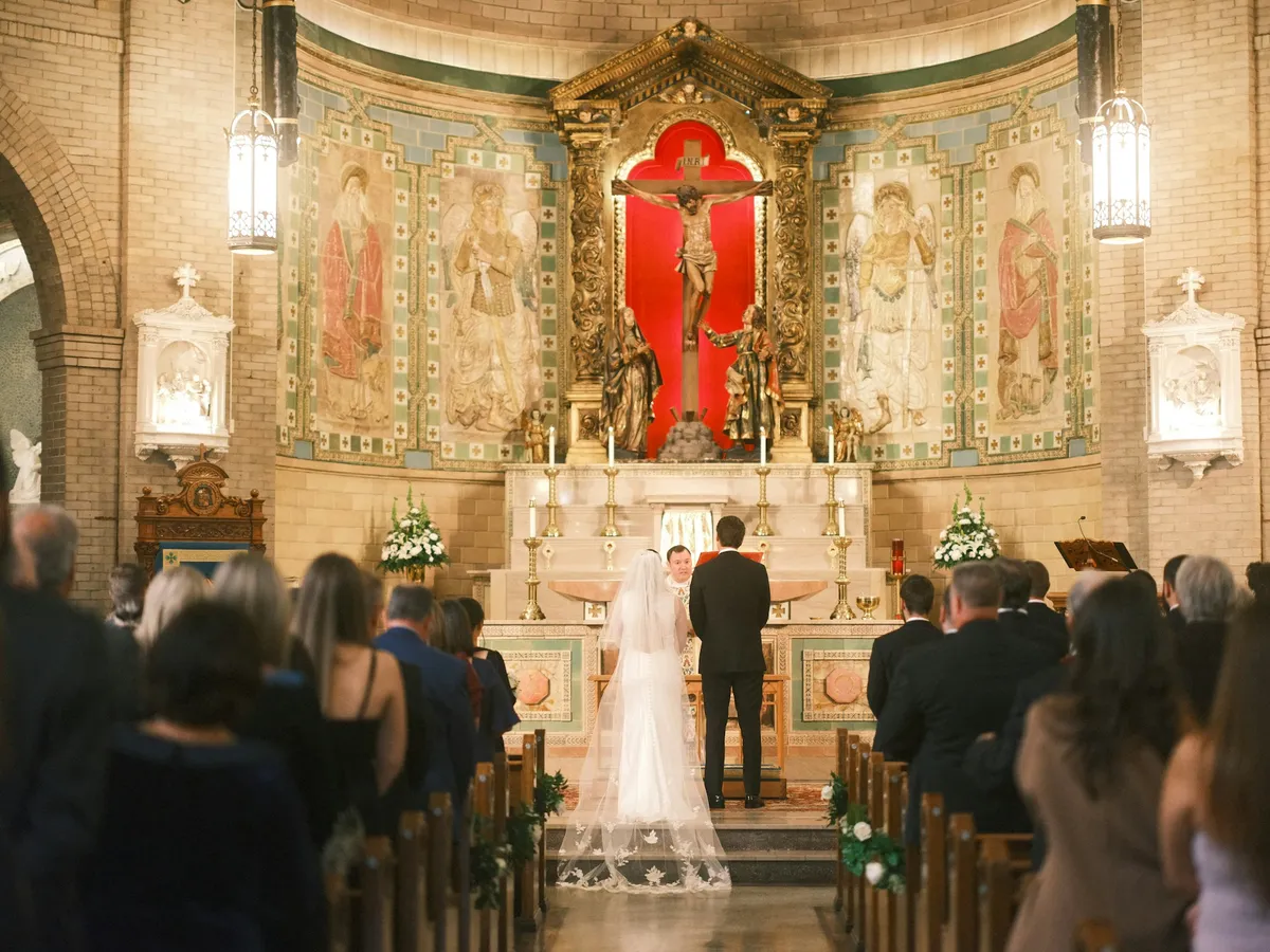 A bride and groom stand before the altar during a church wedding