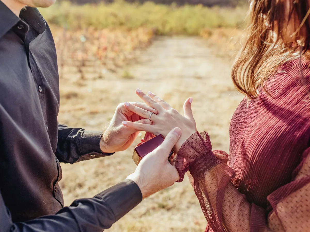 A man slips an engagement ring onto a woman's finger