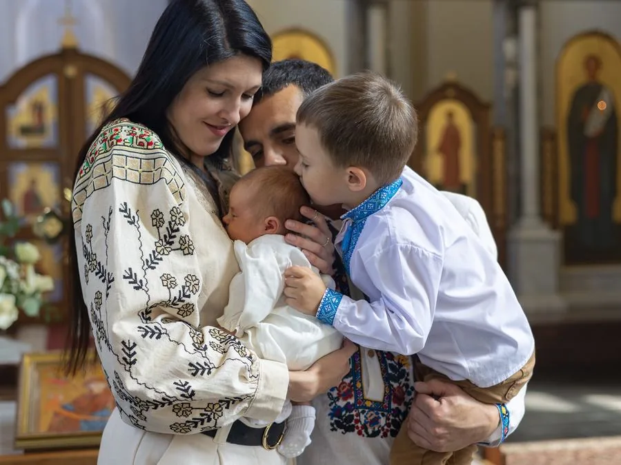 Parents and their children gather around a newborn baby in a church