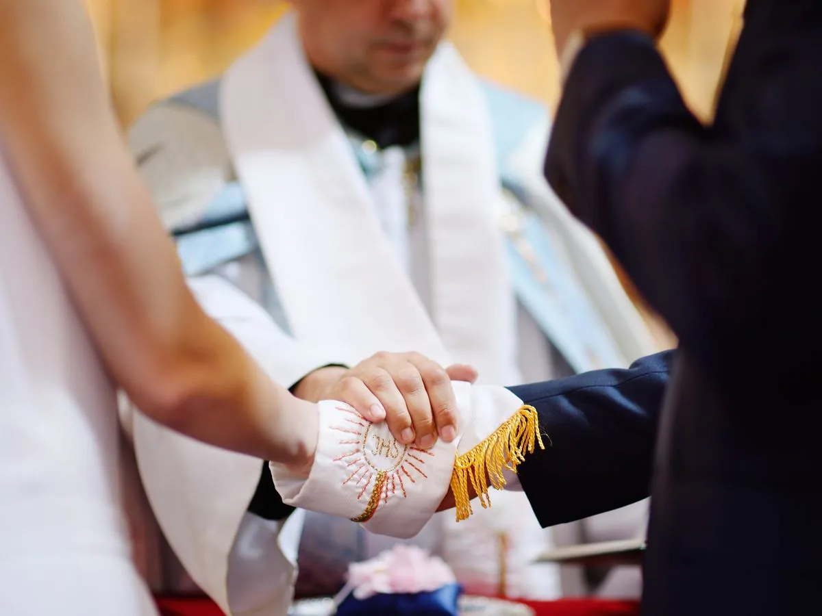 A priest drapes his stole over a bride and groom's joined hands