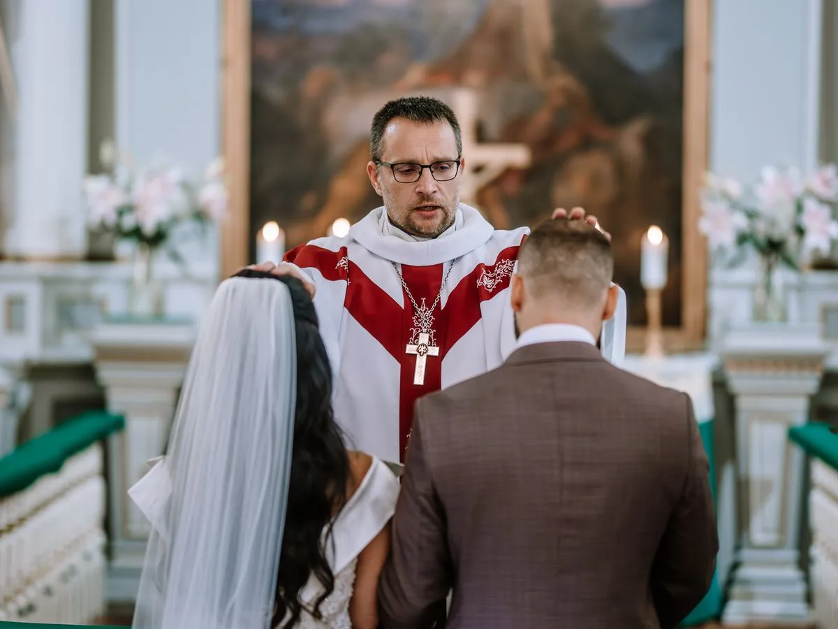 A priest blesses a bride and groom at the altar during their wedding